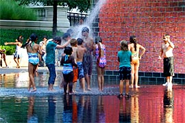 Children of all colors play under fountain